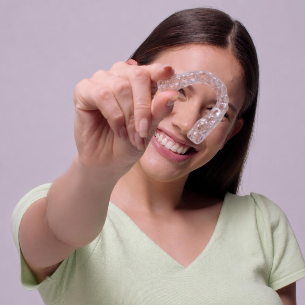 Patient holding a clear aligner and smiling