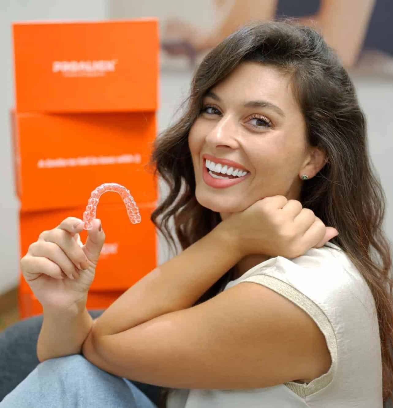 Patient smiling while holding a clear aligner