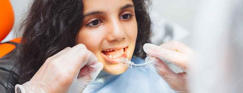Fitting clear aligners on teeth for a child receiving invisalign treatment in dubai